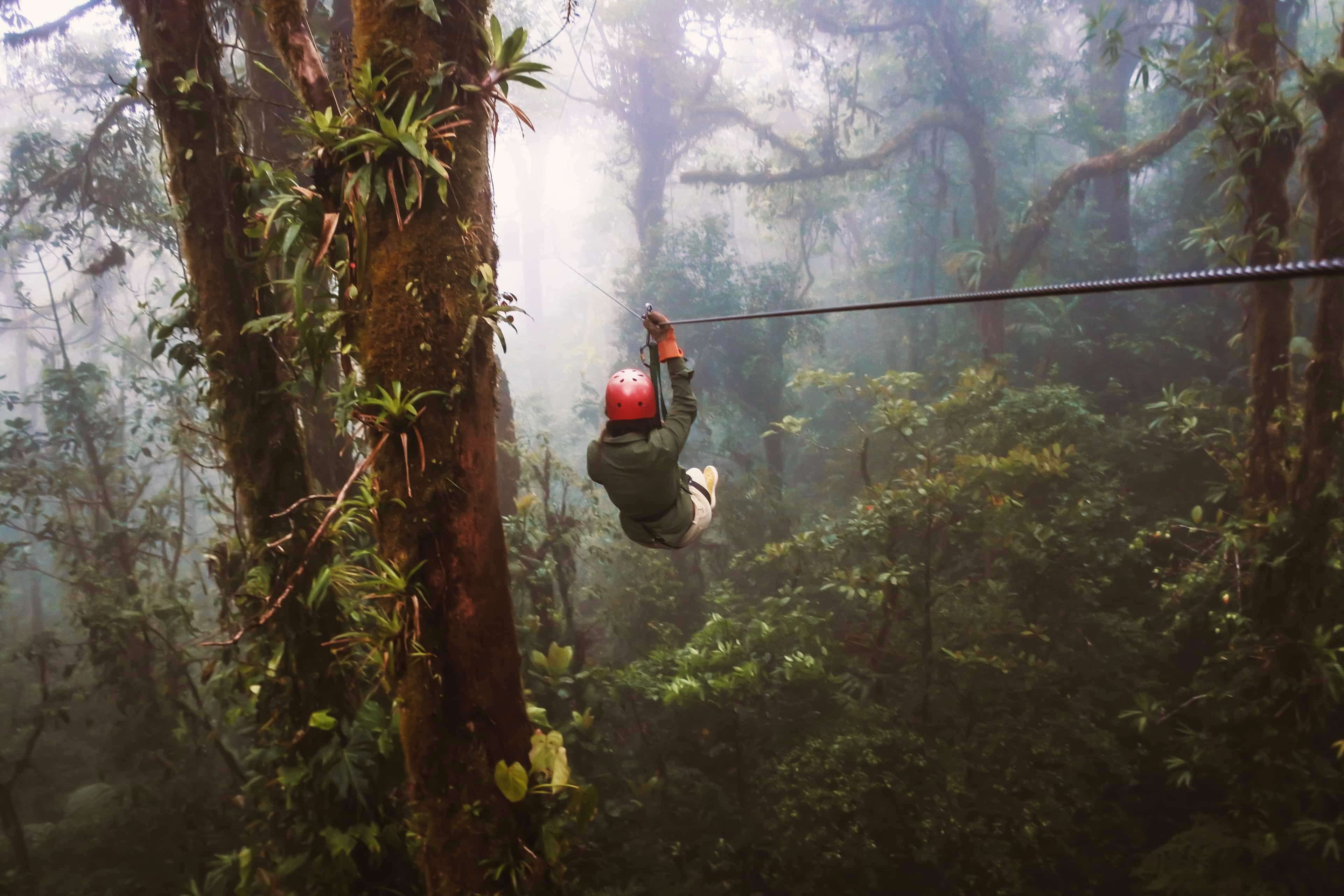Traveller zip-lining through the misty cloud forest canopy in Costa Rica.