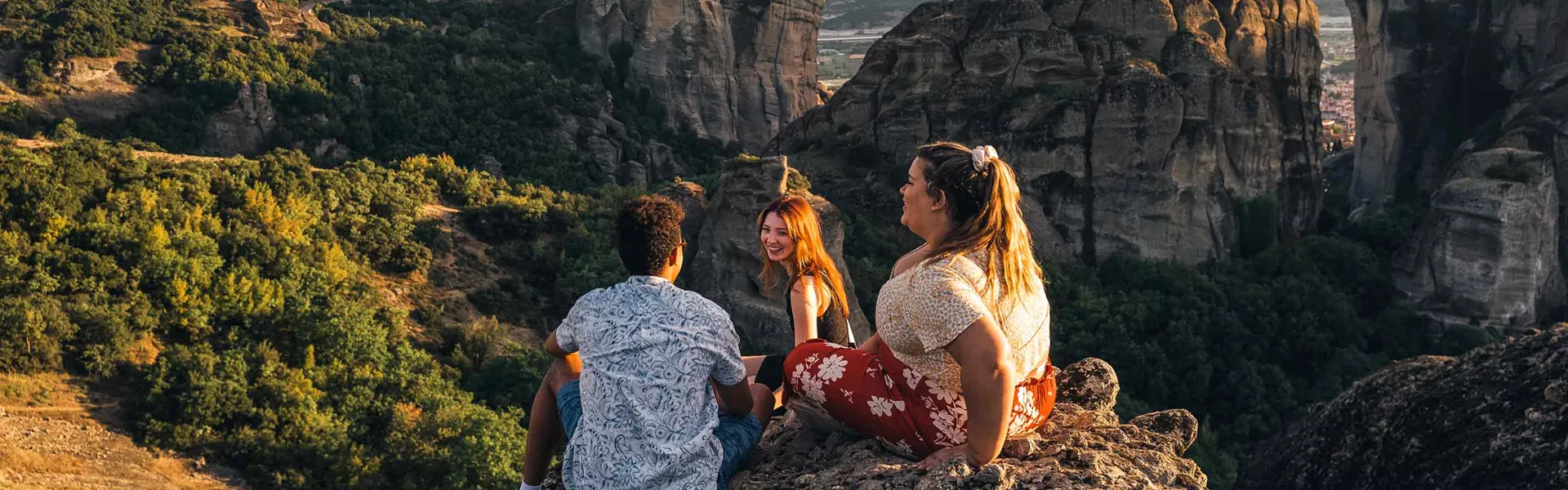Group Sitting On Mountain Over Trees In Greece 