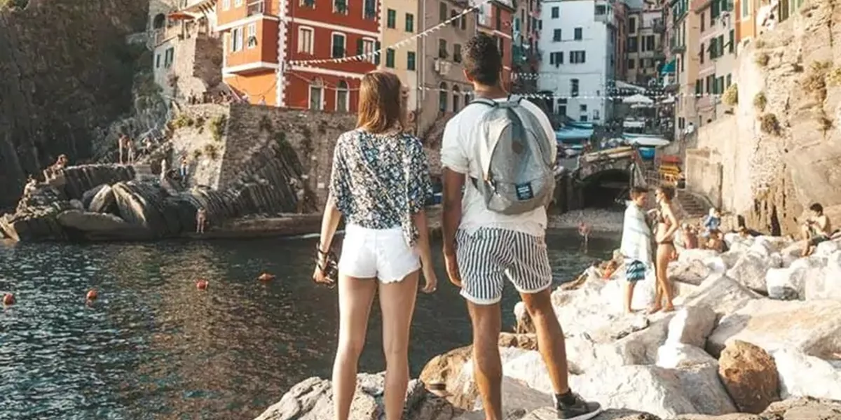  Tourists standing on the rocks and admiring the Italian town