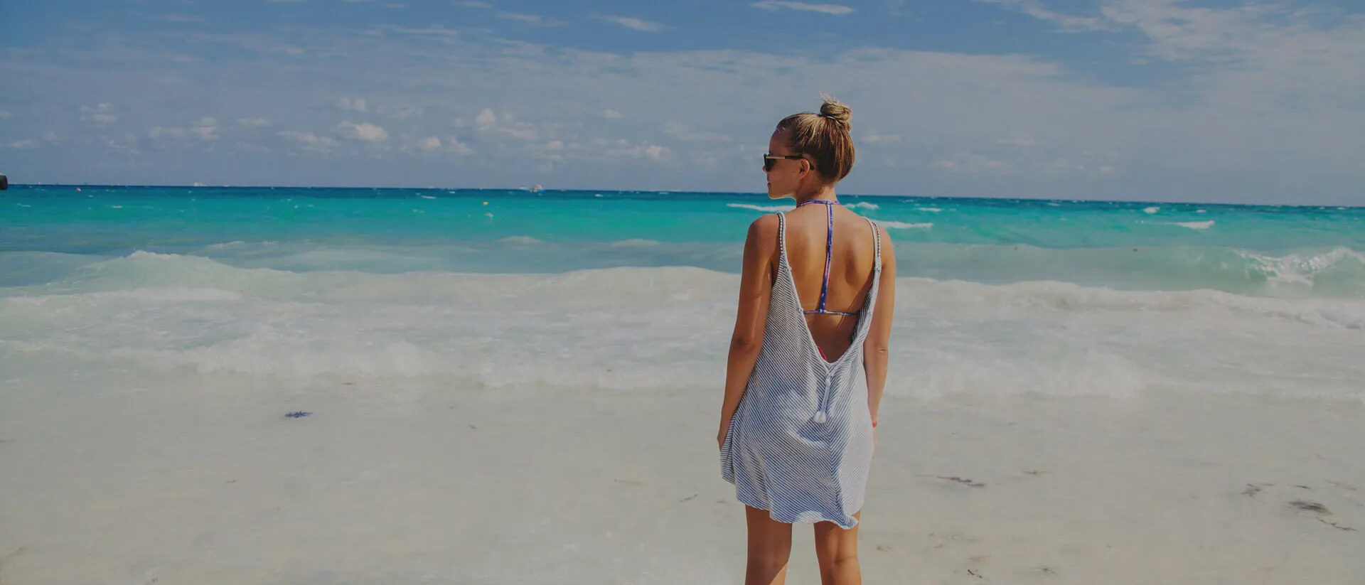 Woman in a blue dress standing on beach in Cancun, Mexico