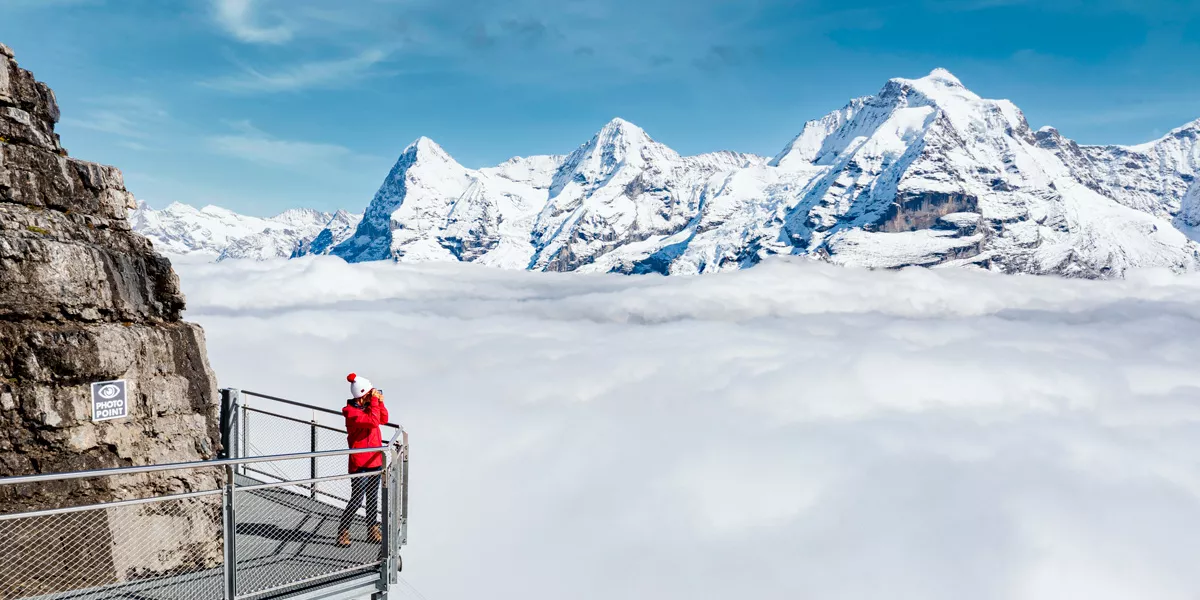 Woman Standing On A High Platform Observing Snowy Mountains
