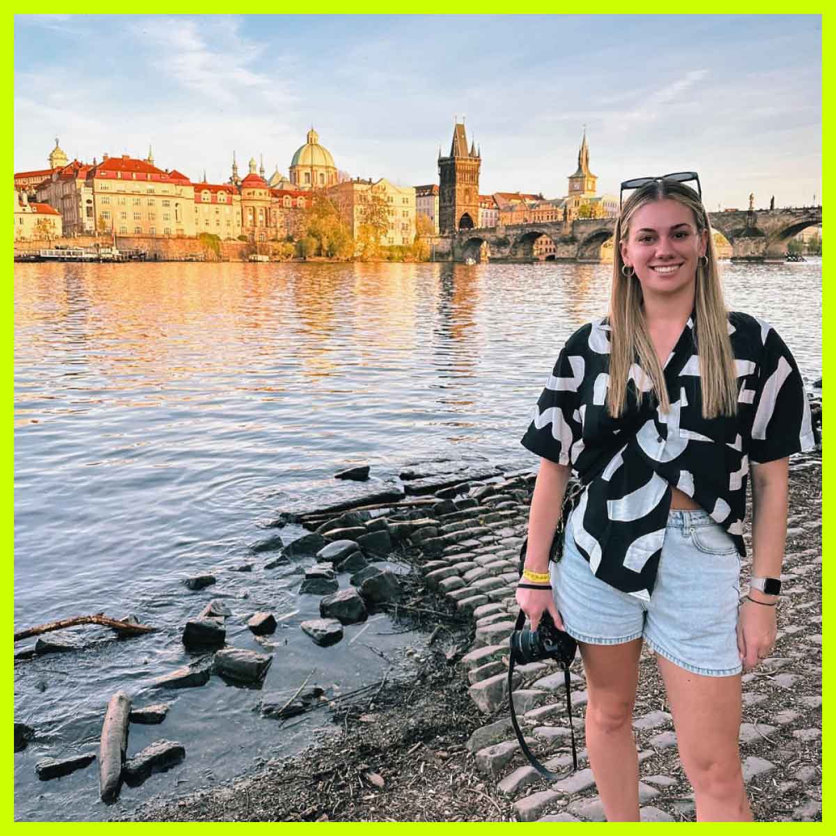 Traveller standing next to the Vltava river in front of the Charles Bridge, Prague, Czech Republic