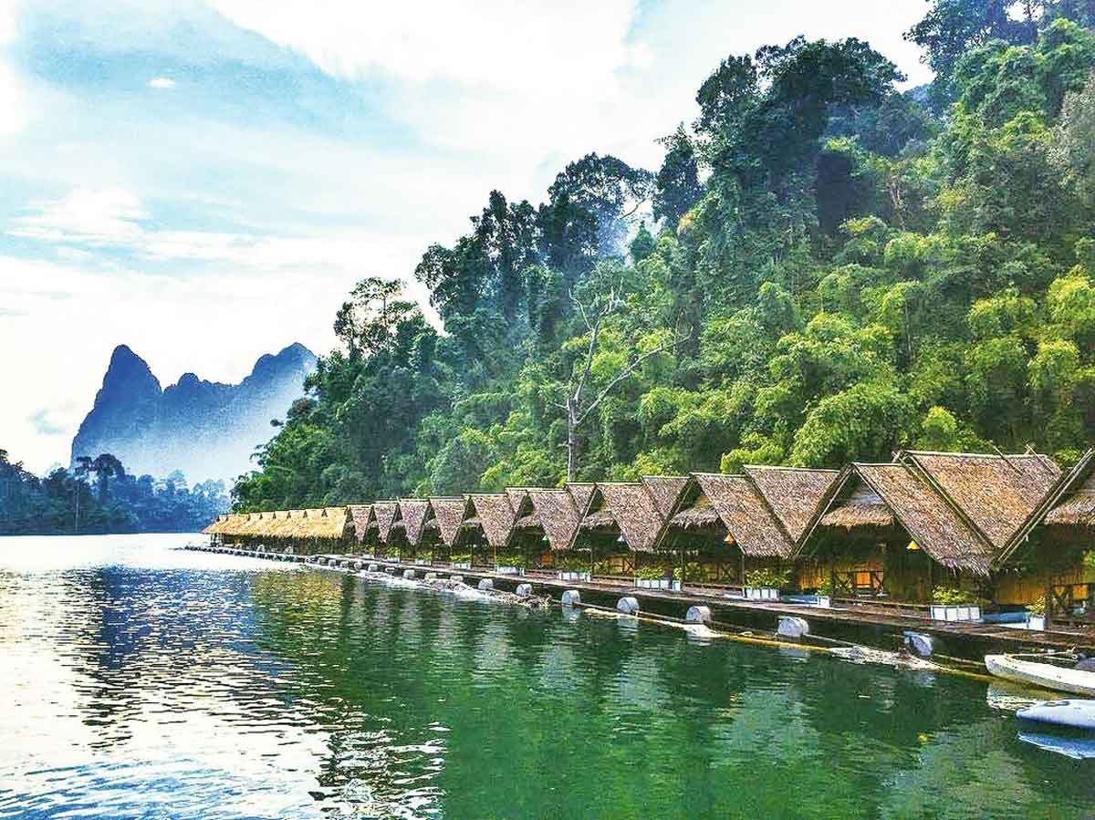 Small Cabains Floating On Water Trees And Green Mountains As Background