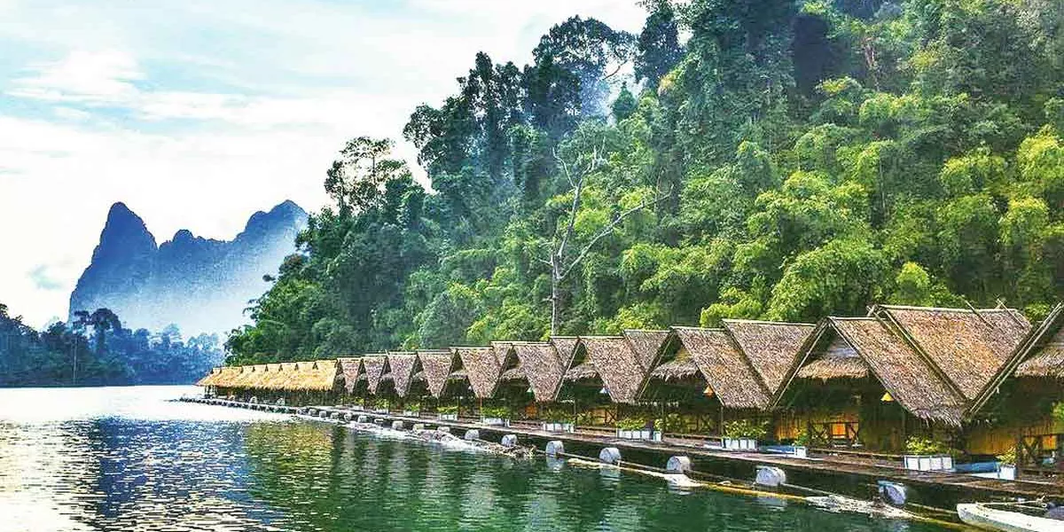 Small Cabains Floating On Water Trees And Green Mountains As Background