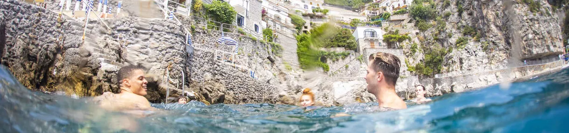 Group Of Travelers Enjoying Swimming In The Sea On Amalfi Coast Italy