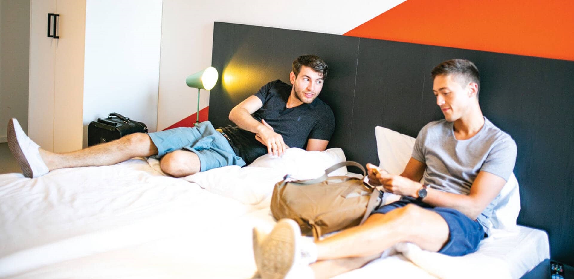 Two men lying on the hotel bed and smilling