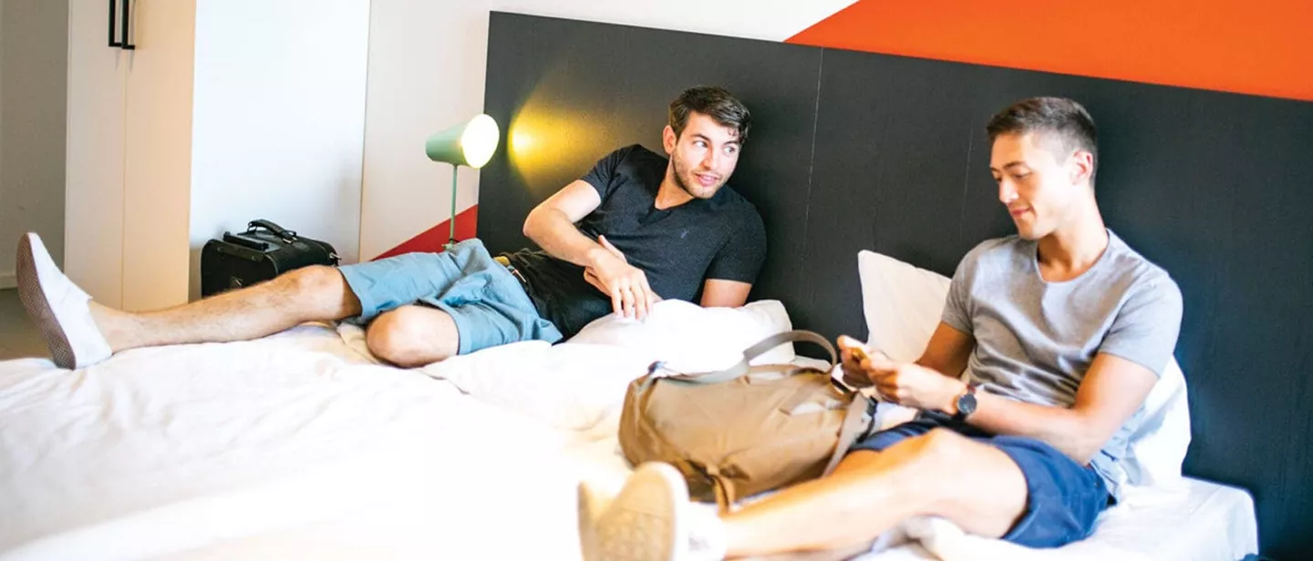 Two men lying on the hotel bed and smilling