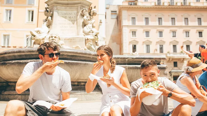 Travellers eating pizza on the steps of a Roman Fountain in Rome, Italy