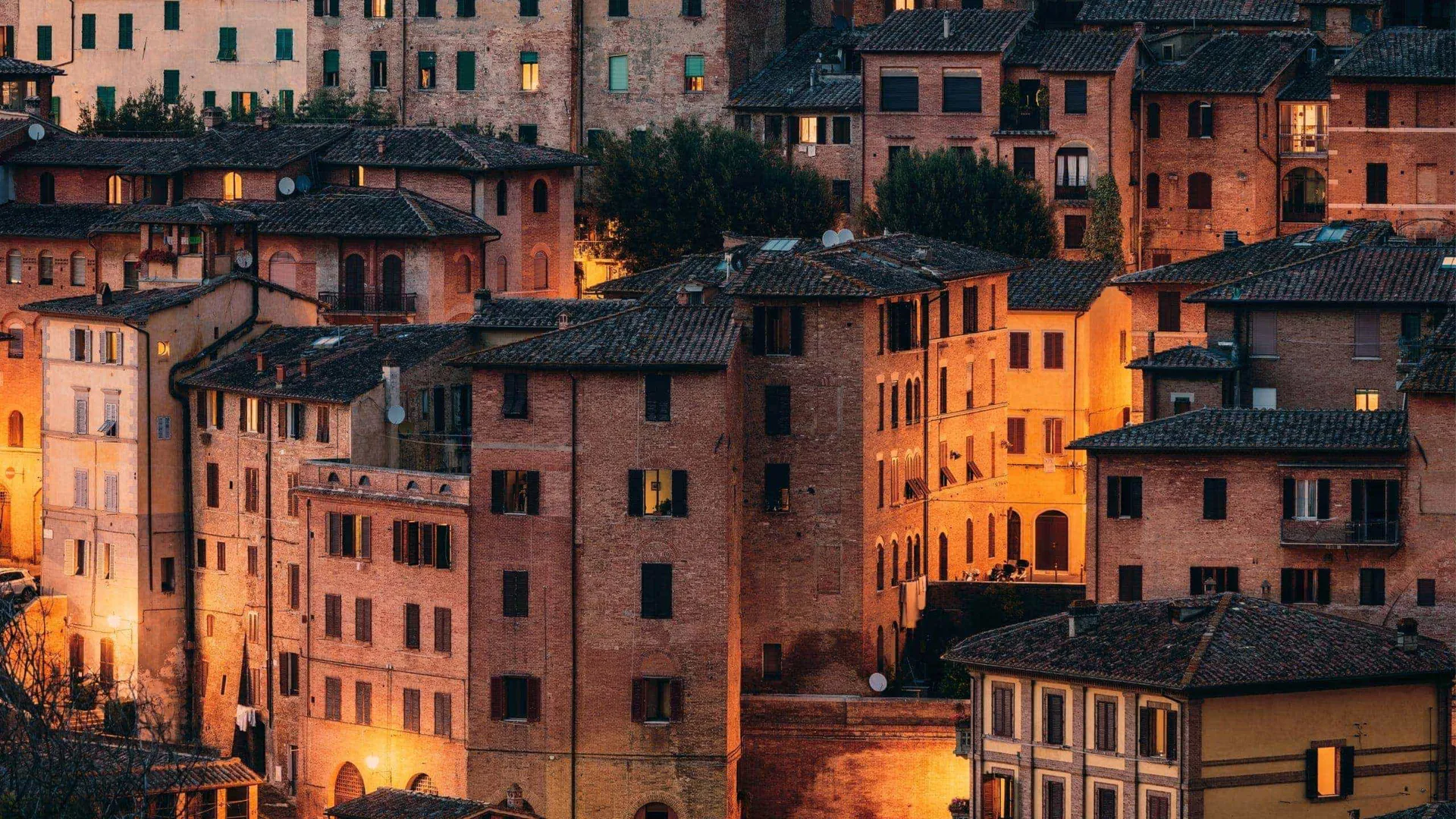 Historic Tuscan town at sunset, featuring terracotta rooftops and traditional Italian architecture on the Contikii Tuscan Escape Tour