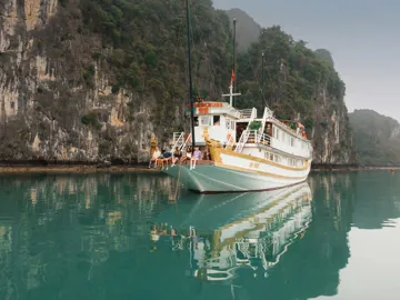 Contiki travellers relaxing aboard an overnight cruise through Ha Long Bay, Vietnam, surrounded by towering limestone karsts on the Ultimate South East Asia Tour