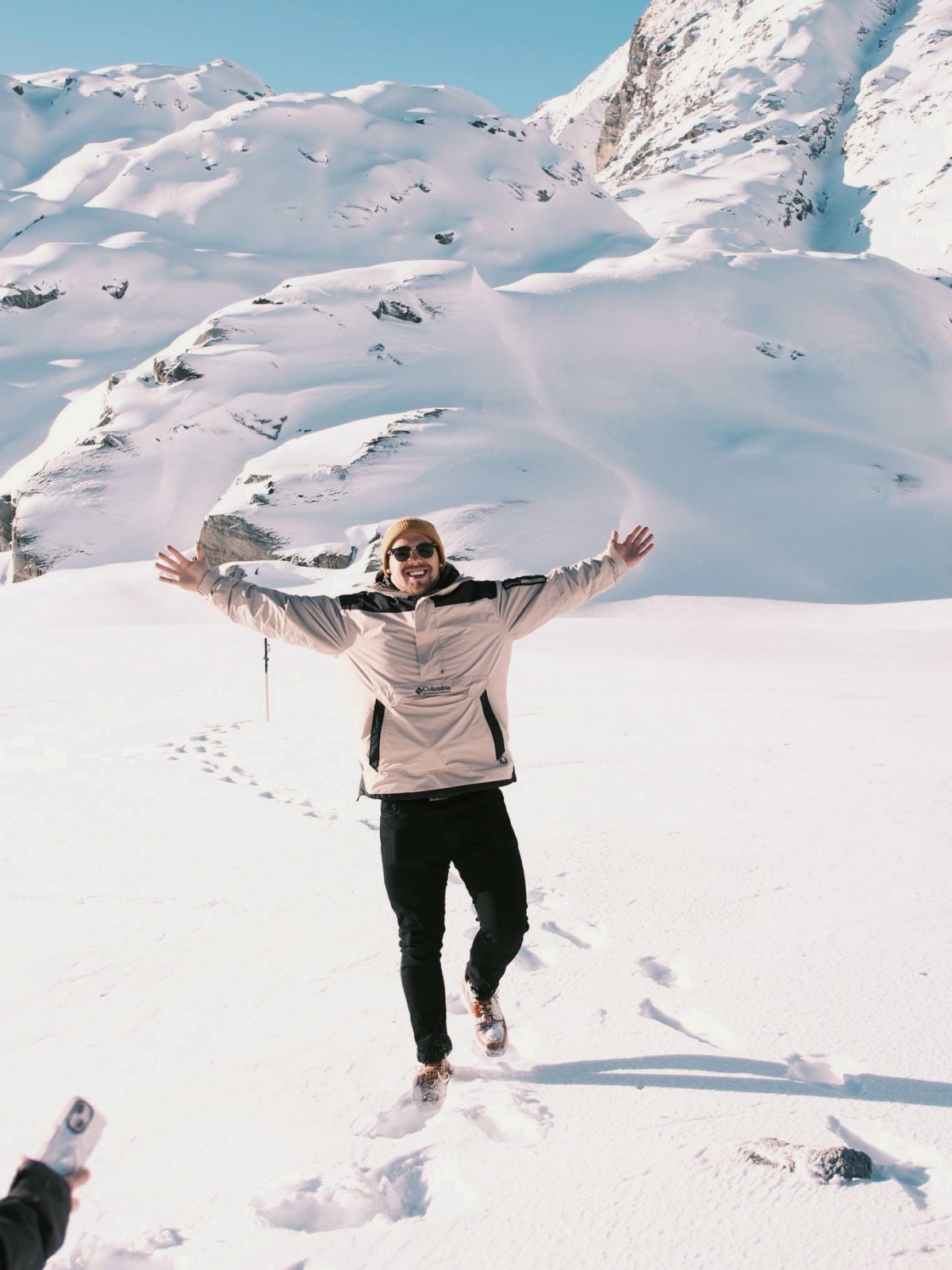 Traveller standing in the snow surrounded by alpine mountains near Queenstown, New Zealand.