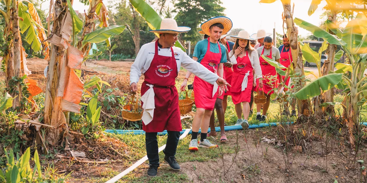 Local man showing plants to travellers for cooking class, Chiang Mai, Thailand