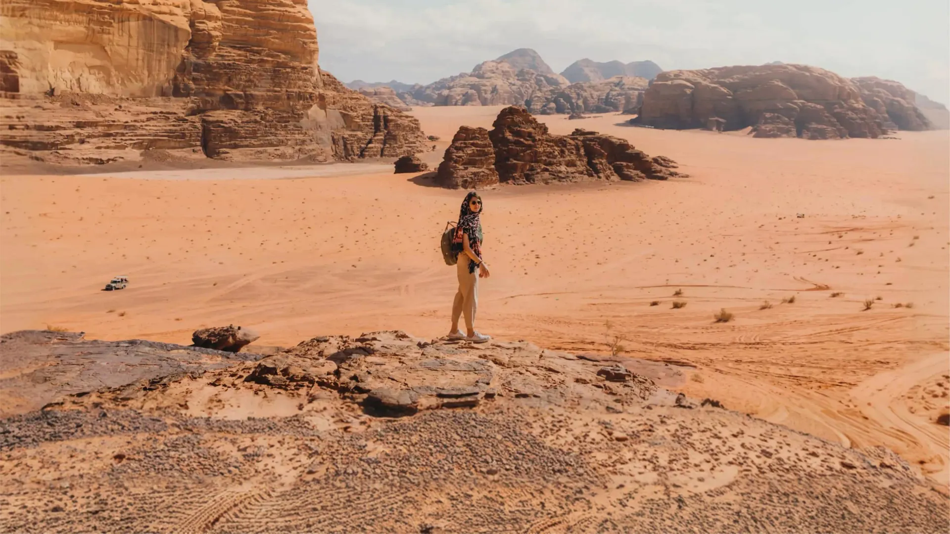 Female traveller on a sandstone rock overlooking the dramatic desert landscape of Wadi Rum Valley of the Moon Jordan - Contiki Jordan Tour