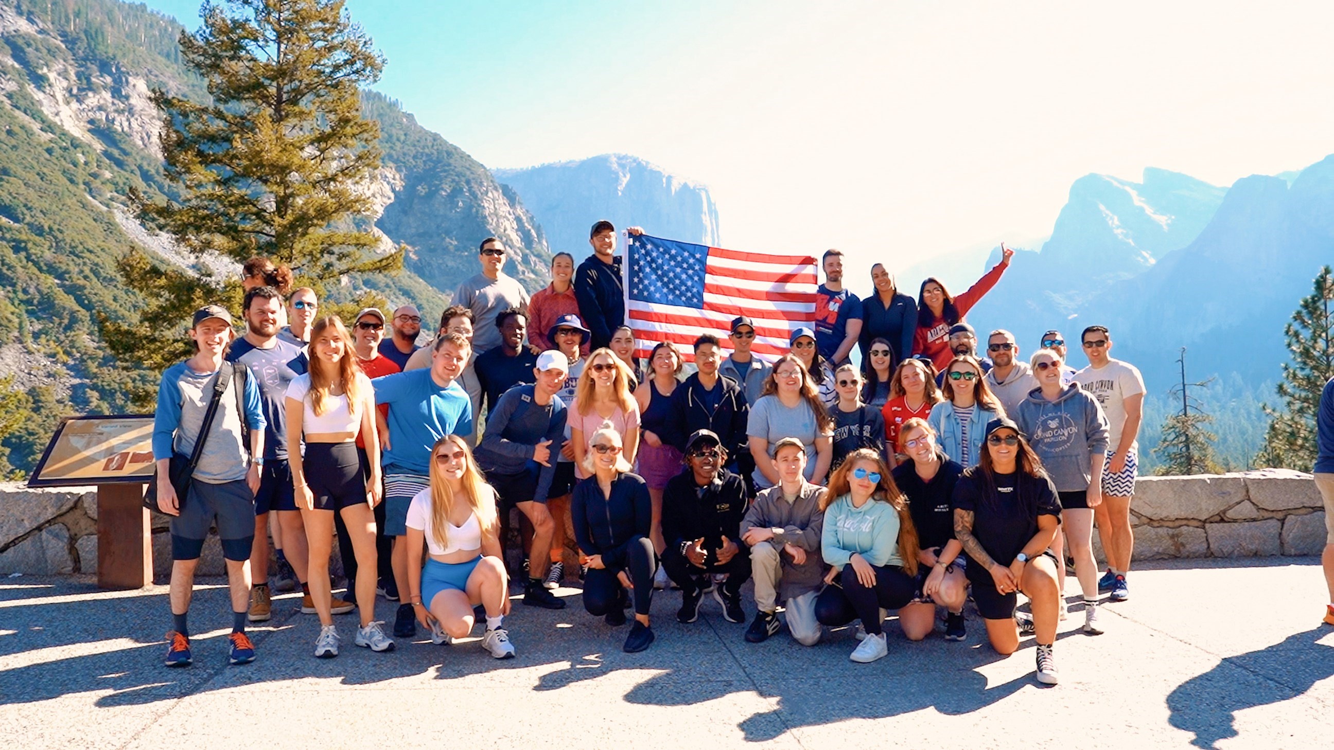 Group of Travellers Posing for Photo with United States Flag at Viewpoint in Yosemite National Park, USA