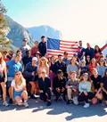 Group of Travellers Posing for Photo with United States Flag at Viewpoint in Yosemite National Park, USA