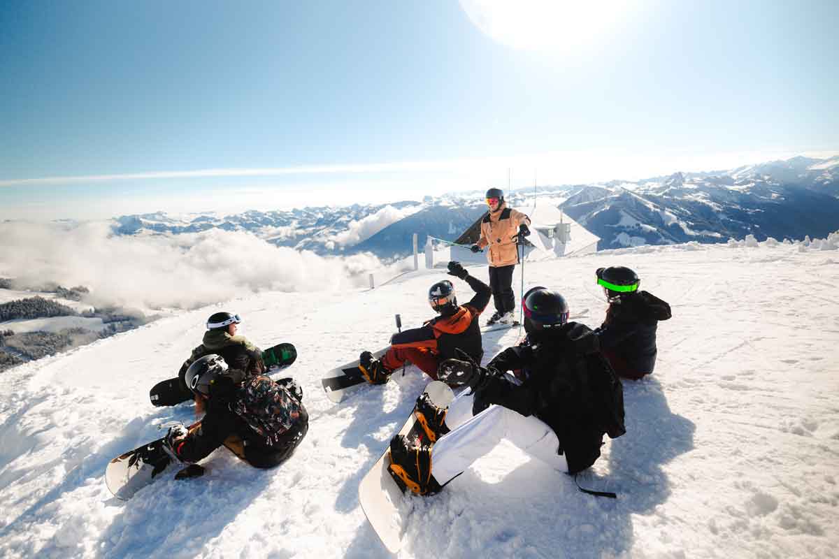 Group Of Snowborders Sat Down On The Slopes In Austria