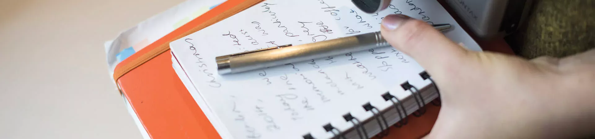 A person holding notebooks, pen and a camera