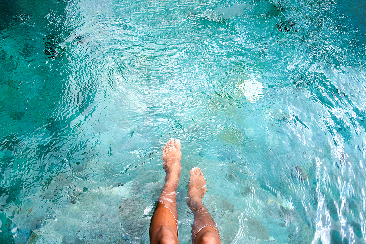Traveller kicking their feet in clear blue water in Tekapo, New Zealand