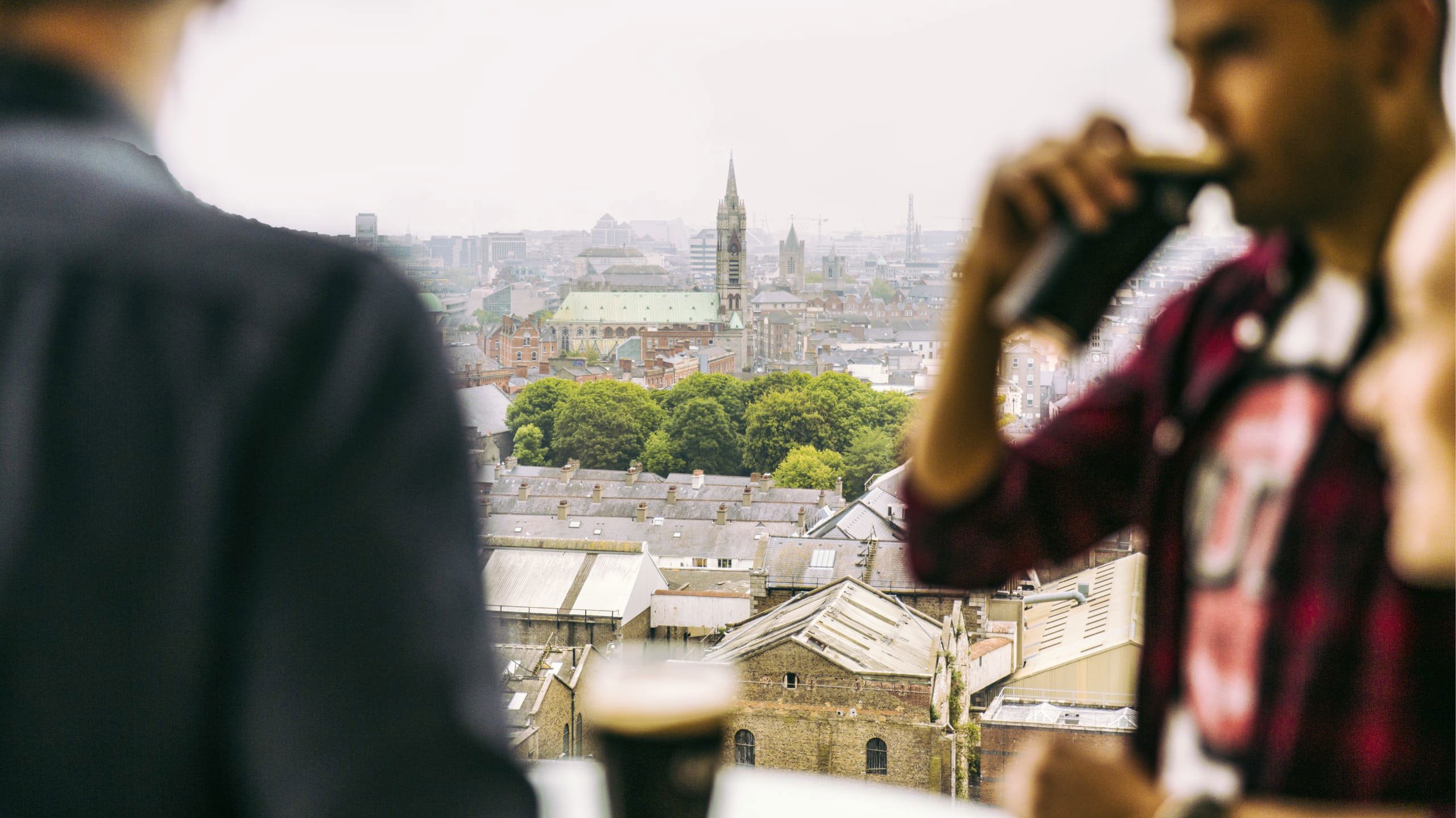 Traveller drinking a pint of Guinness at the Guinness Storehouse rooftop bar overlooking the Dublin city skyline - Contiki St Patrick's Day Festival Tour Ireland