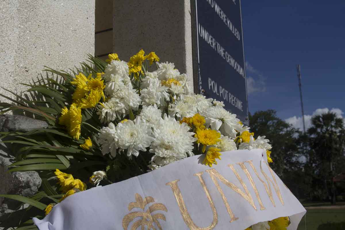 Floral memorial arrangement with white and yellow flowers placed at a genocide remembrance monument