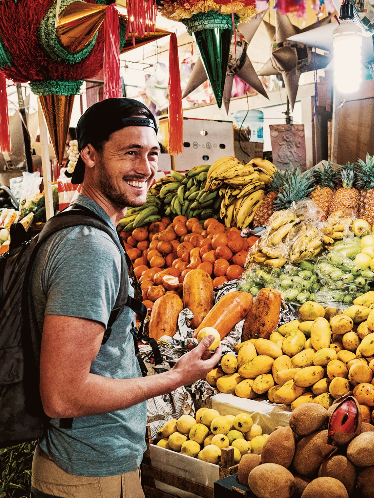 Traveller browsing a colourful fruit stand piled with tropical produce at a local market in Argentina.