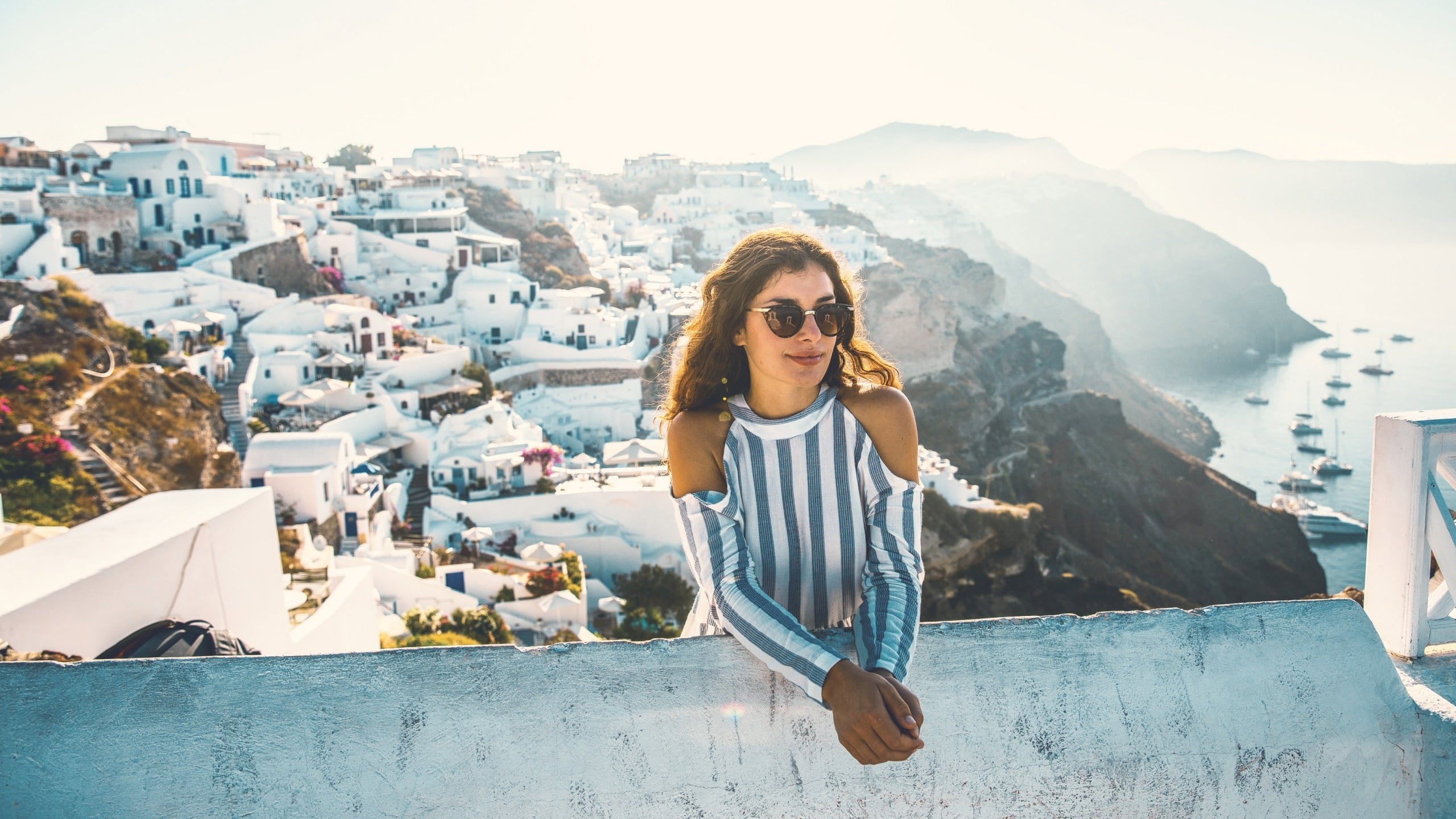 A Contiki traveller overlooks Santorini's whitewashed cliffside village and the Aegean Sea during the London to Santorini Trip