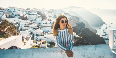 A Contiki traveller overlooks Santorini's whitewashed cliffside village and the Aegean Sea during the London to Santorini Trip