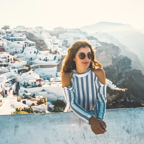 A Contiki traveller overlooks Santorini's whitewashed cliffside village and the Aegean Sea during the London to Santorini Trip