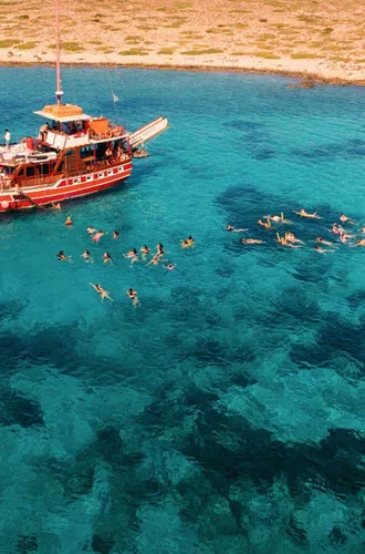 Contiki travellers swimming and snorkelling in the stunning turquoise waters of the Greek Islands from a traditional wooden gulet boat on a Greek island hopping Tour