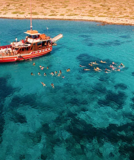 Contiki travellers swimming and snorkelling in the stunning turquoise waters of the Greek Islands from a traditional wooden gulet boat on a Greek island hopping Tour