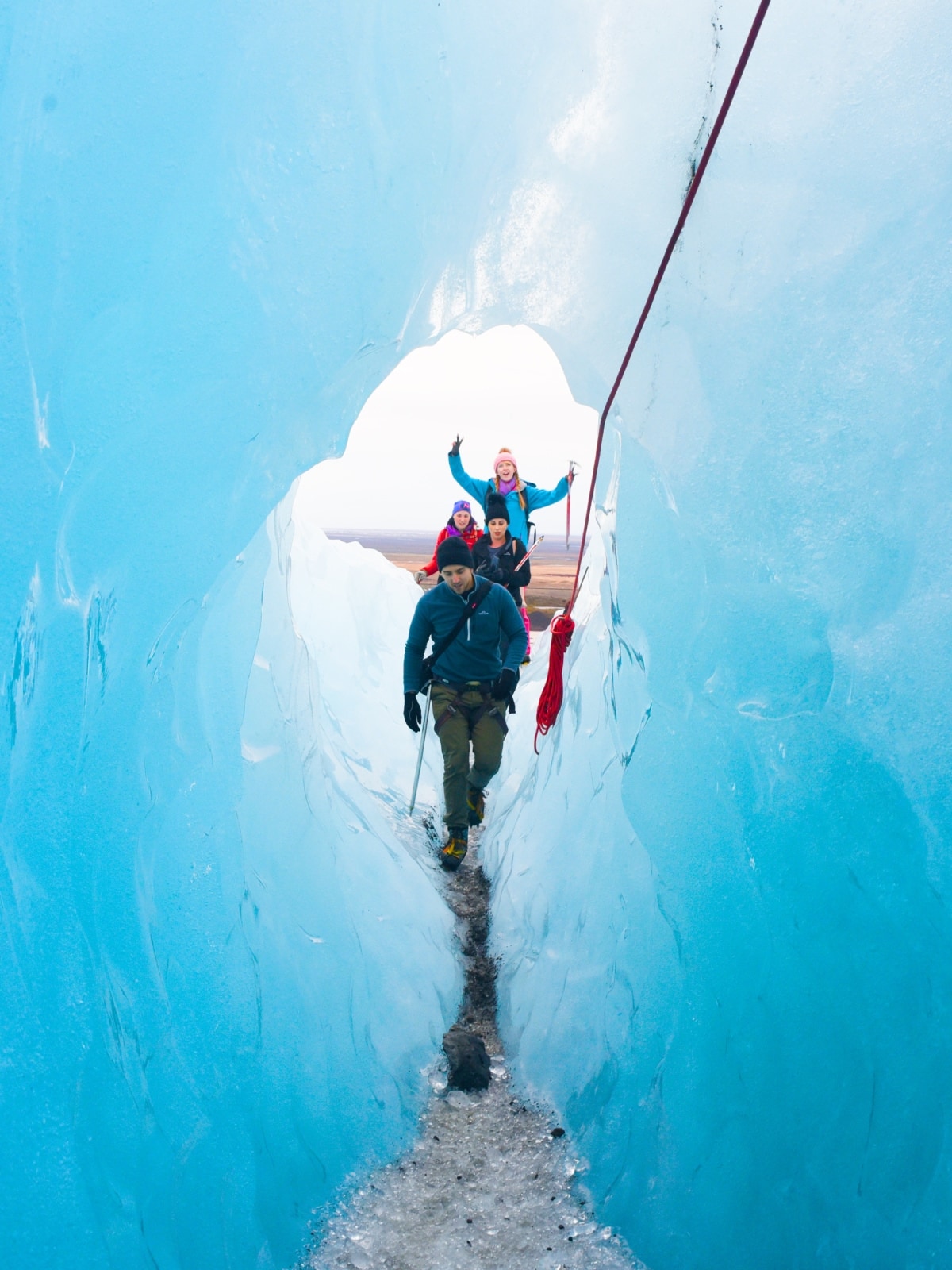 Travellers hiking through a blue ice cave on a guided glacier adventure in Iceland.