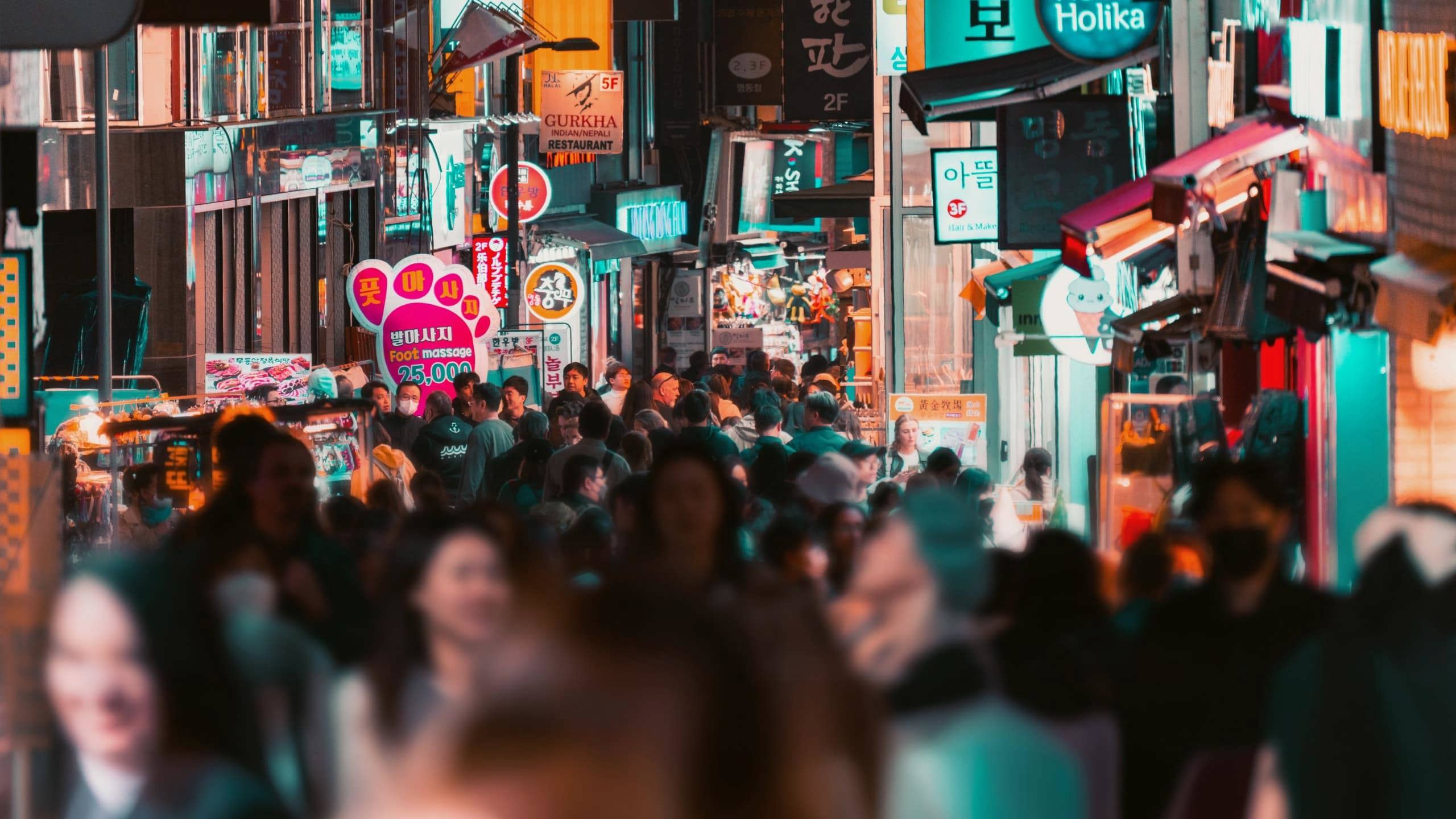 Travellers explore a bustling shopping street filled with neon signs and local stores in Seoul on the Contiki Best of South Korea Tour