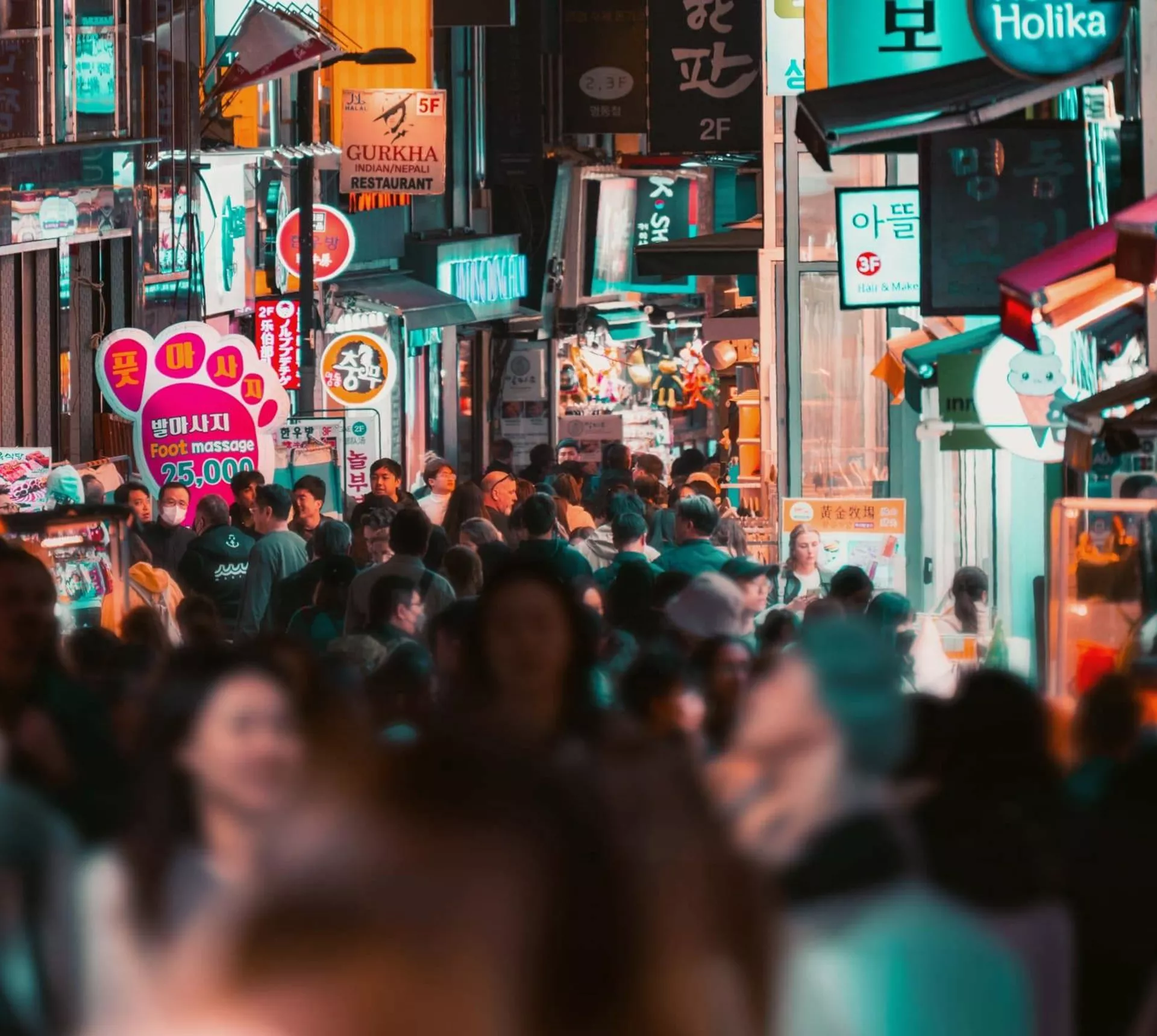 Travellers explore a bustling shopping street filled with neon signs and local stores in Seoul on the Contiki Best of South Korea Tour