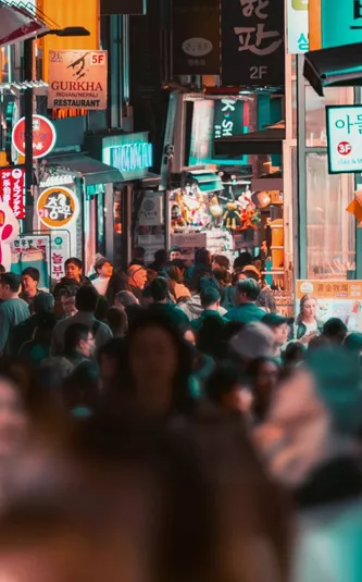 Travellers explore a bustling shopping street filled with neon signs and local stores in Seoul on the Contiki Best of South Korea Tour