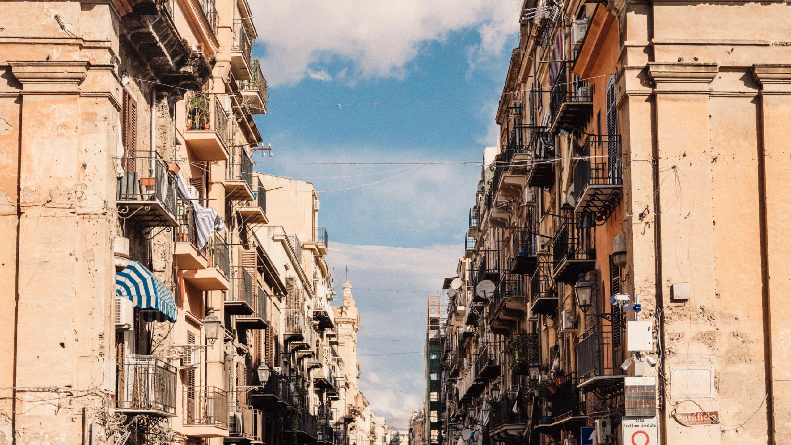 Historic street in Sicily, Italy, lined with colourful buildings and balconies on the Contiki Sicily Escape Tour
