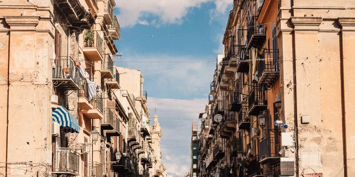Historic street in Sicily, Italy, lined with colourful buildings and balconies on the Contiki Sicily Escape Tour