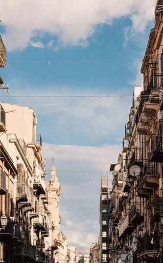 Historic street in Sicily, Italy, lined with colourful buildings and balconies on the Contiki Sicily Escape Tour
