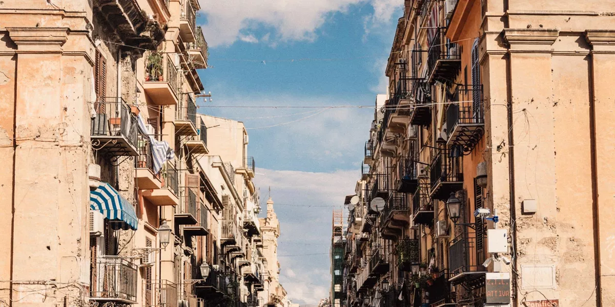 Historic street in Sicily, Italy, lined with colourful buildings and balconies on the Contiki Sicily Escape Tour