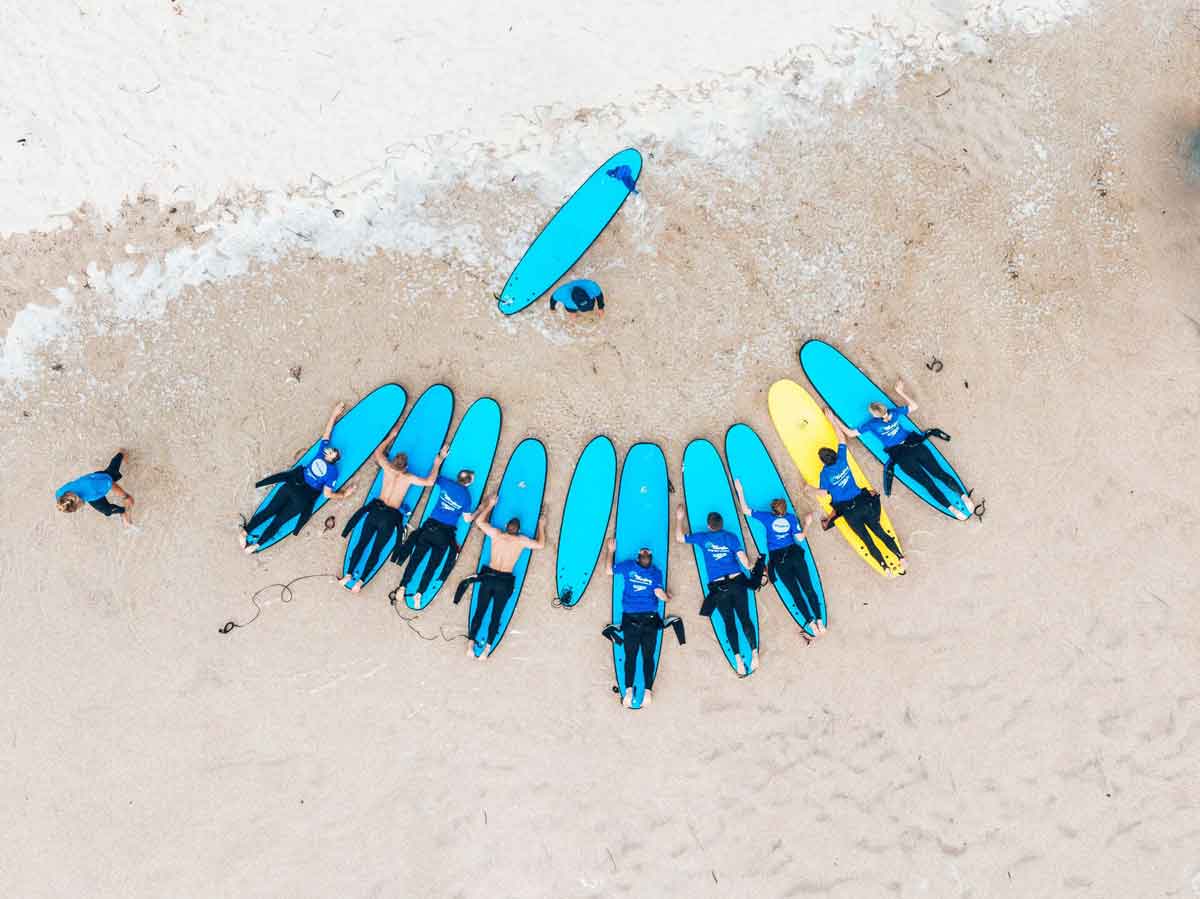People Practicing Surfing On The Sand