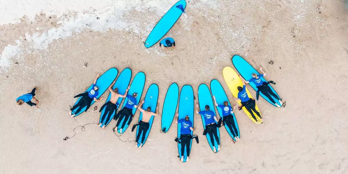 People Practicing Surfing On The Sand