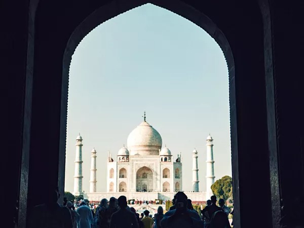 View of the Taj Mahal from a large gate people walking towards it in India.