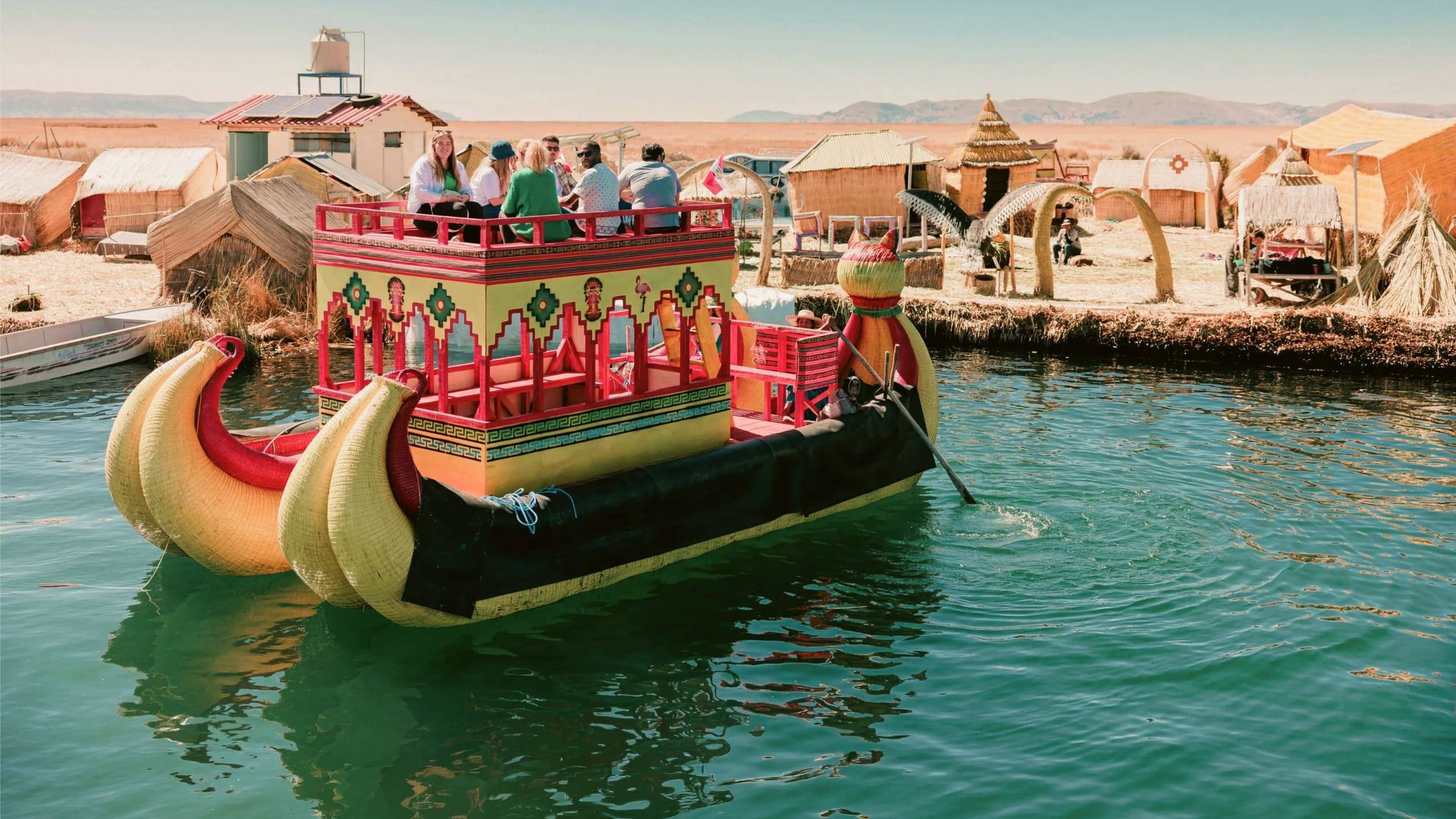 Contiki travellers cruising on a traditional reed boat at the Uros Floating Islands on Lake Titicaca, experiencing local culture on the Peru Uncovered Tour