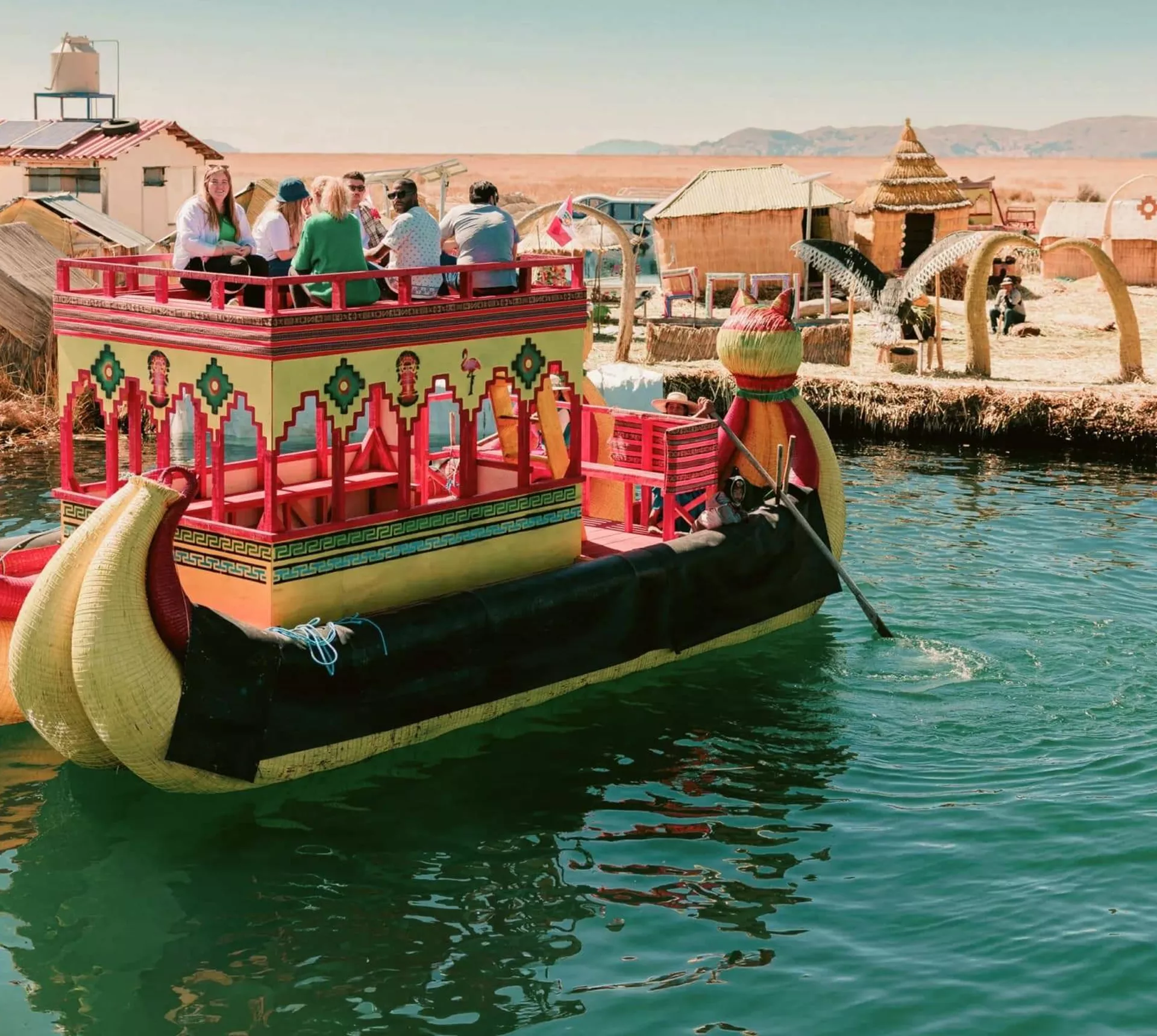Contiki travellers cruising on a traditional reed boat at the Uros Floating Islands on Lake Titicaca, experiencing local culture on the Peru Uncovered Tour