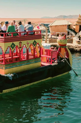 Contiki travellers cruising on a traditional reed boat at the Uros Floating Islands on Lake Titicaca, experiencing local culture on the Peru Uncovered Tour