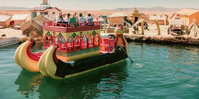 Contiki travellers cruising on a traditional reed boat at the Uros Floating Islands on Lake Titicaca, experiencing local culture on the Peru Uncovered Tour
