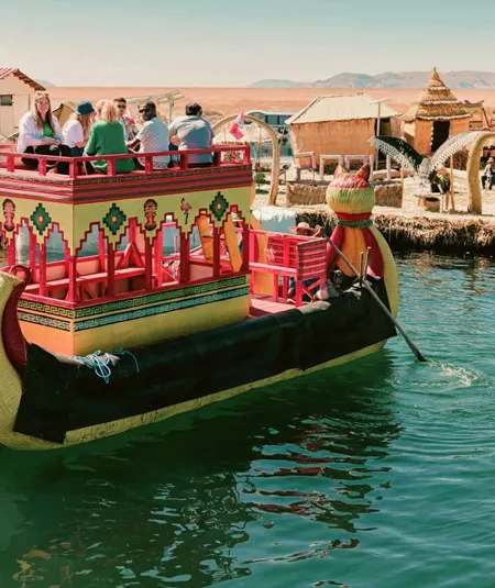 Contiki travellers cruising on a traditional reed boat at the Uros Floating Islands on Lake Titicaca, experiencing local culture on the Peru Uncovered Tour