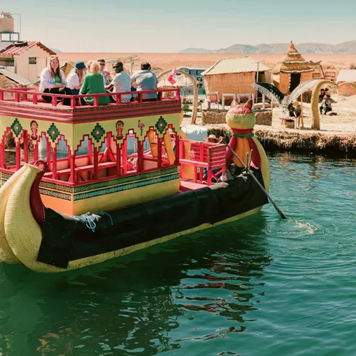 Contiki travellers cruising on a traditional reed boat at the Uros Floating Islands on Lake Titicaca, experiencing local culture on the Peru Uncovered Tour