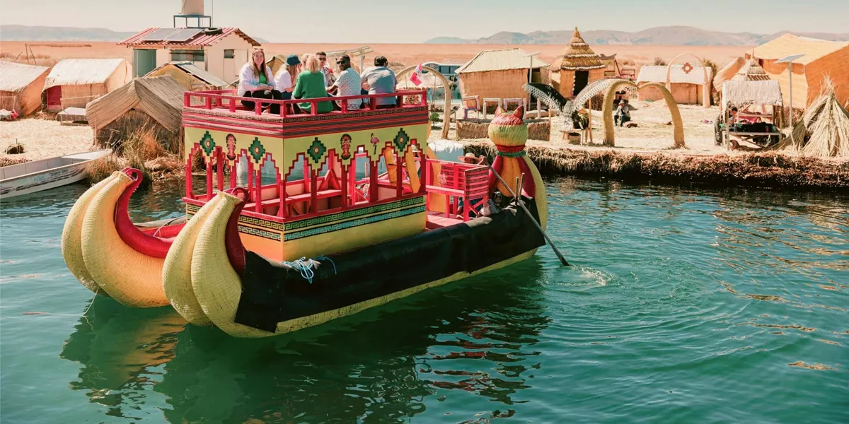 Contiki travellers cruising on a traditional reed boat at the Uros Floating Islands on Lake Titicaca, experiencing local culture on the Peru Uncovered Tour