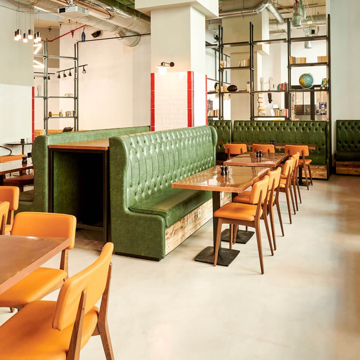 Generator Hostel with green couches, wooden tables and orange chairs