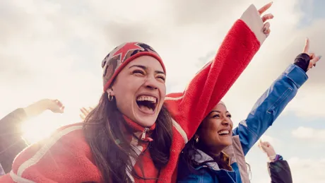 Travellers cheer and laugh with arms raised at the Snow Machine music festival in New Zealand.